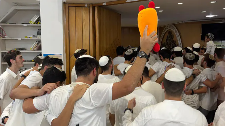 Soldier dances in yeshiva holding stuffed Torah scroll