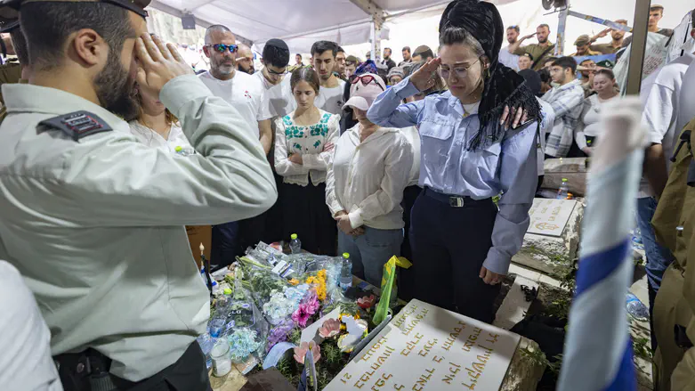 During the siren, Miriam Dickshtein salutes besides her fallen husband’s grave