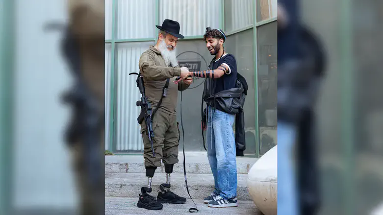 Gun and Prosthetics: War amputee puts on tefillin after losing both legs