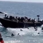 Tourists flee as dozens of migrants storm Spanish beach from boat | Watch
