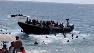 Tourists flee as dozens of migrants storm Spanish beach from boat | Watch